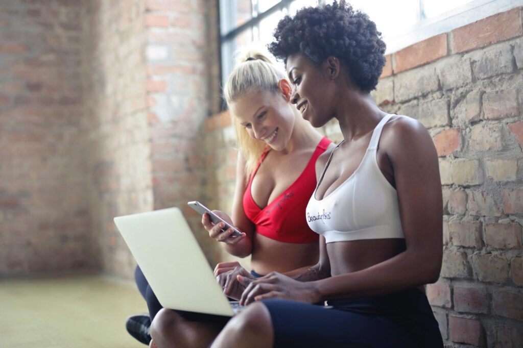 two women sitting down near wall at the gym